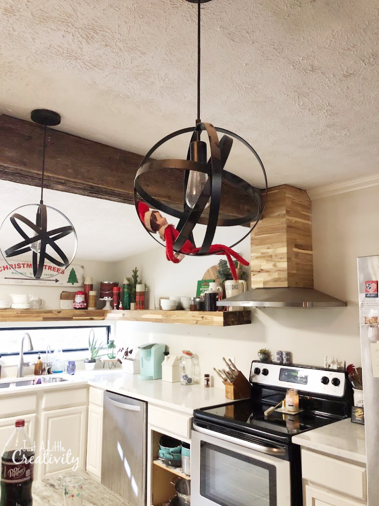 Elf on the Shelf hanging from a kitchen light fixture