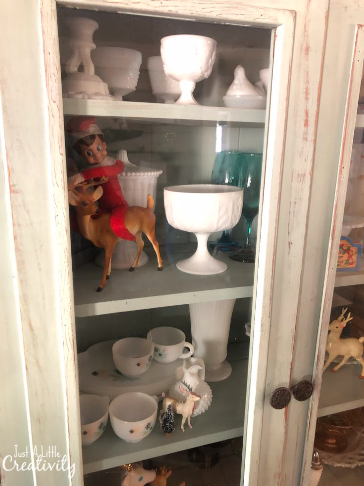 Elf on the Shelf hiding in the china cabinet